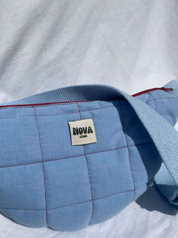 Blue quilted bag with 'NOVA' label on a white background
