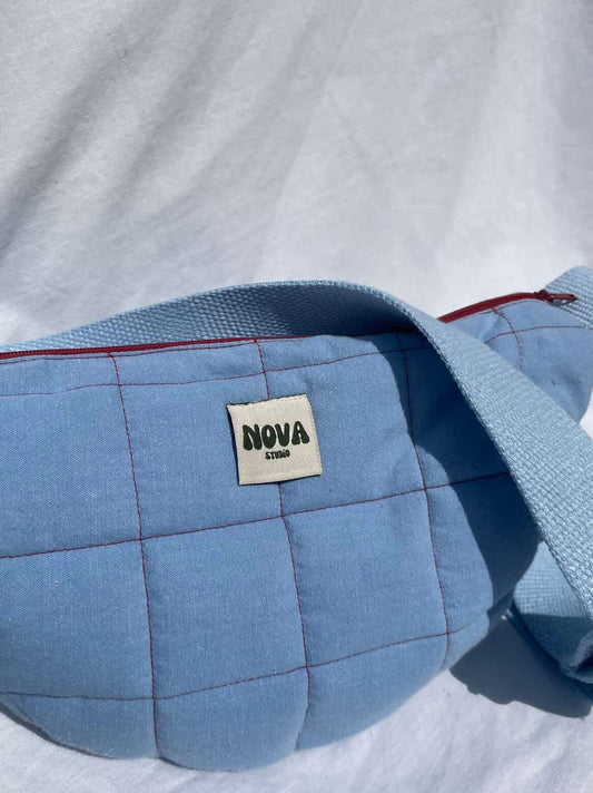 Blue quilted bag with 'NOVA' label on a white background