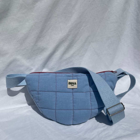 Blue quilted waist bag with a visible brand logo on a light gray background
