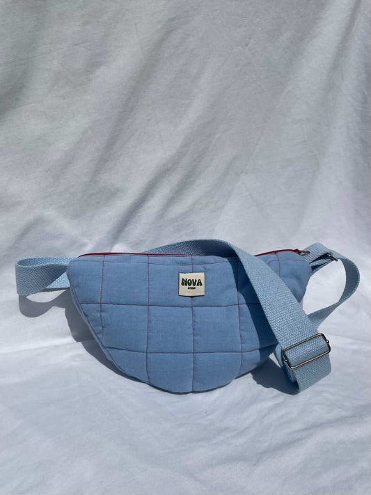 Blue quilted waist bag with a visible brand logo on a light gray background