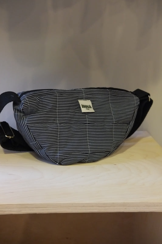 A NAVY and white striped fanny pack with a white brand label reading 'MUGLER', resting on a light wood surface against a neutral gray background.