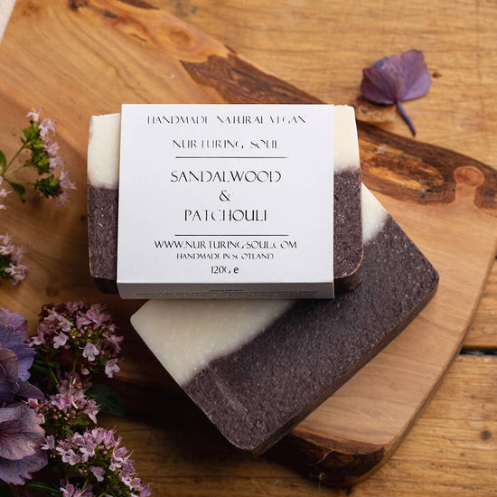 A bar of two tones soap on a wooden background with flowers surrounding 