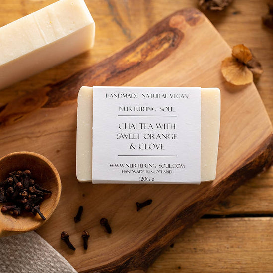 A soap bar on a wooden background surrounded by cloves 