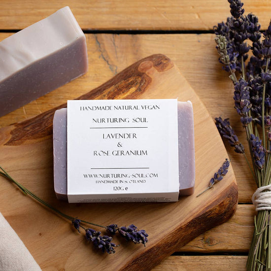 A lilac coloured bar of soap on a wooden background with lavender flowers 