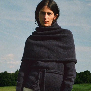 Woman wearing a dark blue knitted shawl in a field