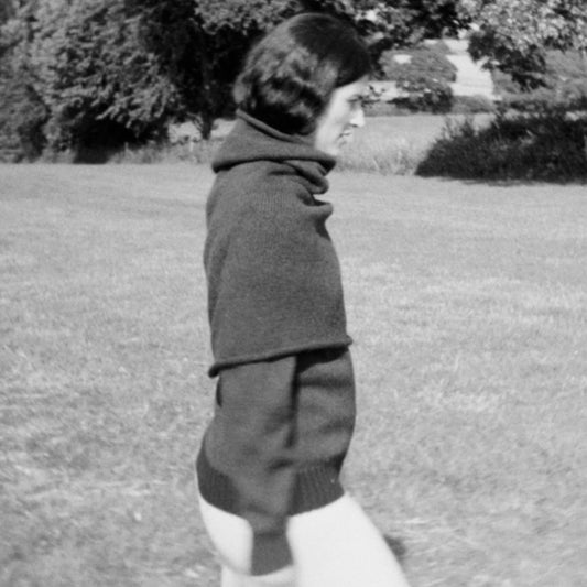 Person standing in a grassy field with trees in the background