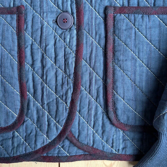 Pocket and button details on a blue quilted jacket 