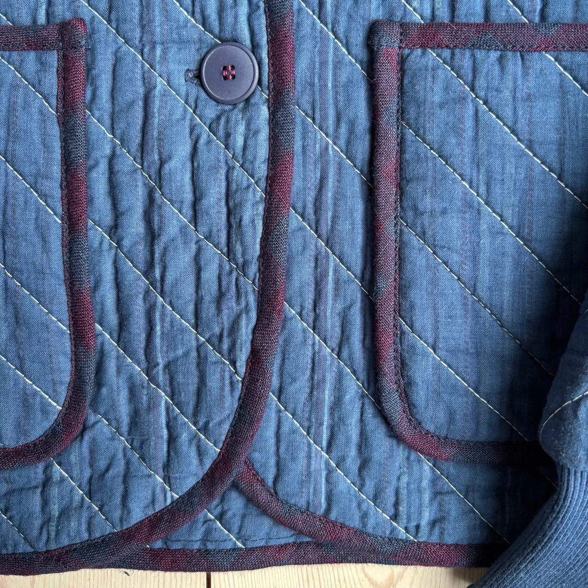 Pocket and button details on a blue quilted jacket 