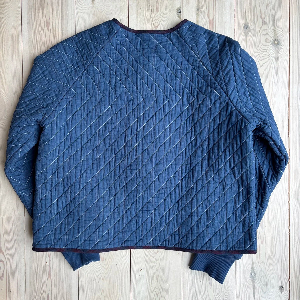 The back detailing of a blue jacket on a wooden floor 