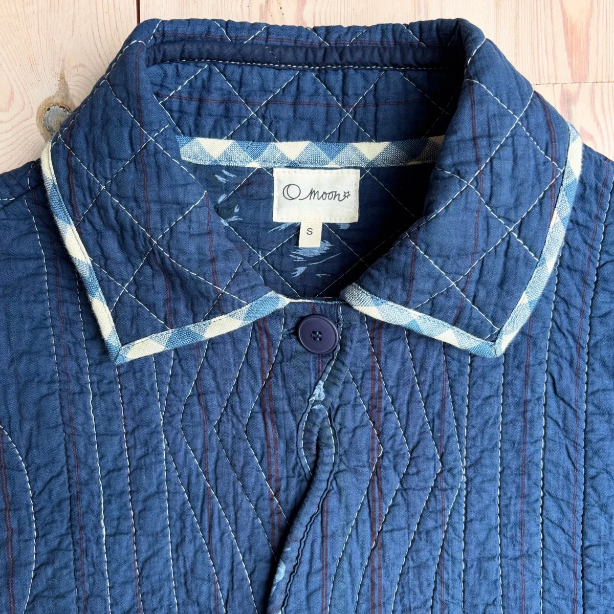 Collar detailing of a blue jacket with a blue and white contest piping 