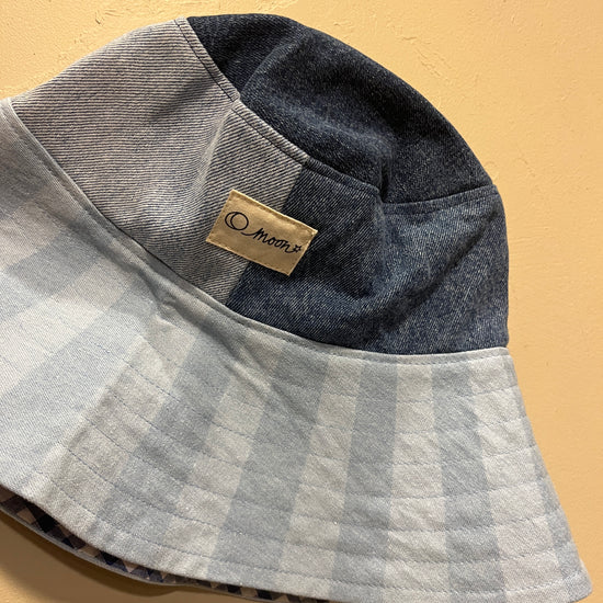 Patch denim bucket hat with large brim on a beige background