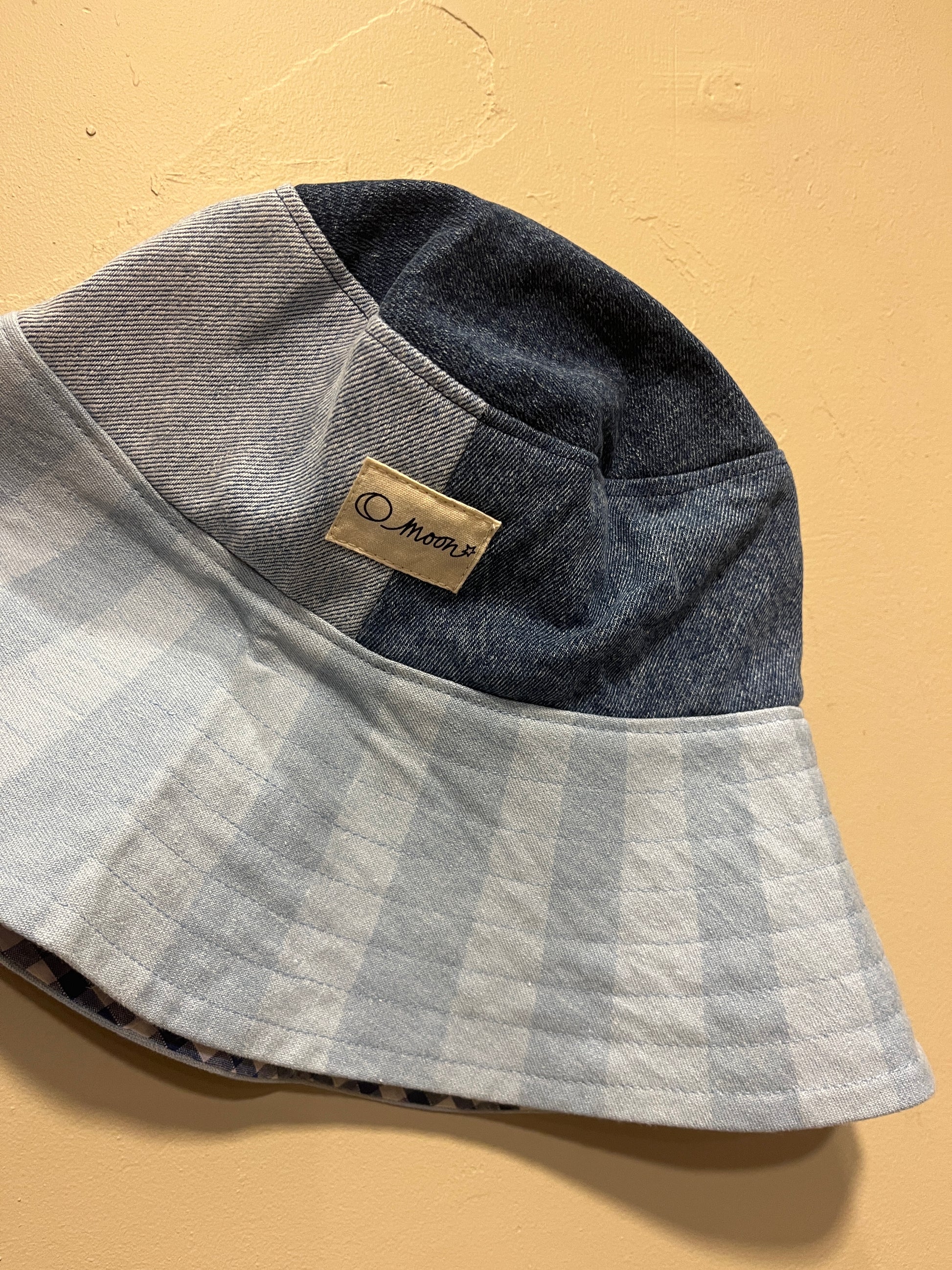 Patch denim bucket hat with large brim on a beige background