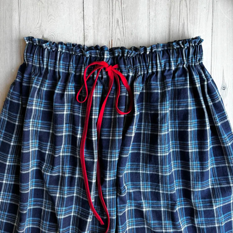 Blue plaid shorts with a red drawstring on a wooden surface