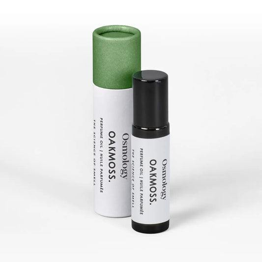 A small black roll-on bottle labeled 'Osmology OAKMOSS' stands in front of its white cylindrical packaging tube with a green cap on a clean white background.