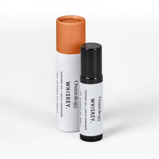 A small white cylindrical bottle with a black cap stands in front of a larger white tube with a copper-orange cap. Both containers are labeled 'Osmology Whiskey' on a clean white background.