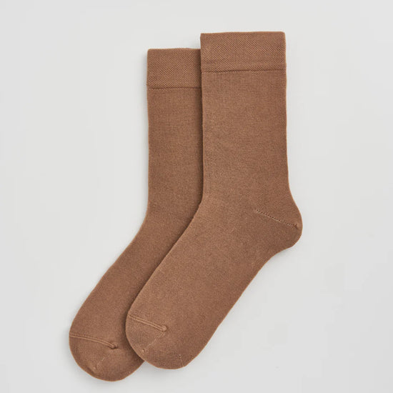 Pair of beige socks on a light grey background