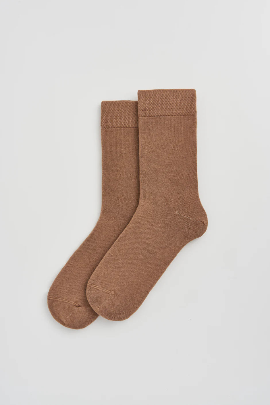 Pair of beige socks on a light grey background