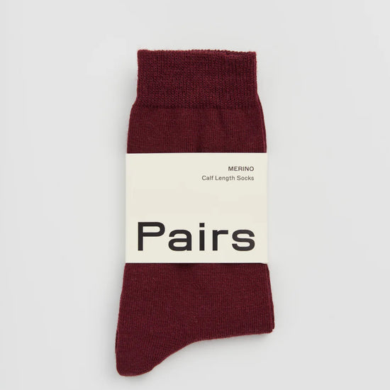 Dark plum sock with a white label on a light grey background