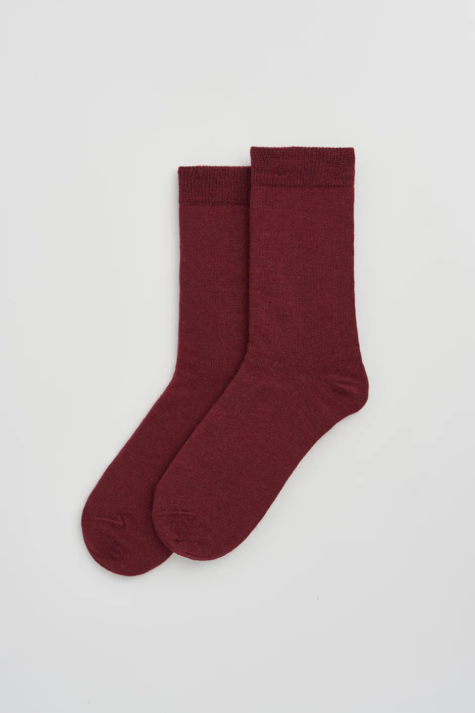 Pair of plum coloured socks on a light grey background