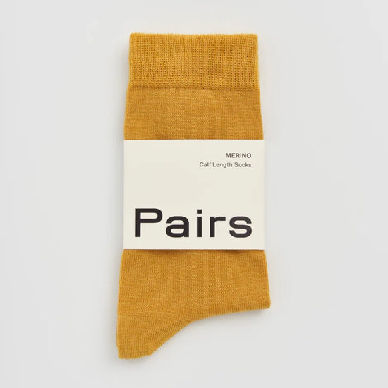 Mustard yellow sock with 'Pairs' label on a light grey background