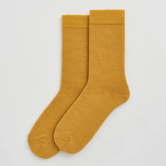 Pair of mustard yellow socks on a light grey background