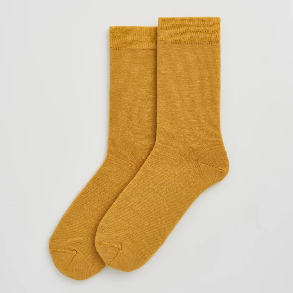 Pair of mustard yellow socks on a light grey background