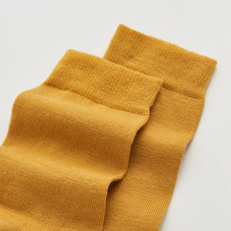 Pair of mustard yellow socks on a light grey background