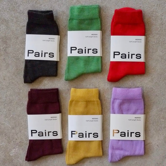 Six pairs of colorful socks with 'Pairs' labels on a textured surface
