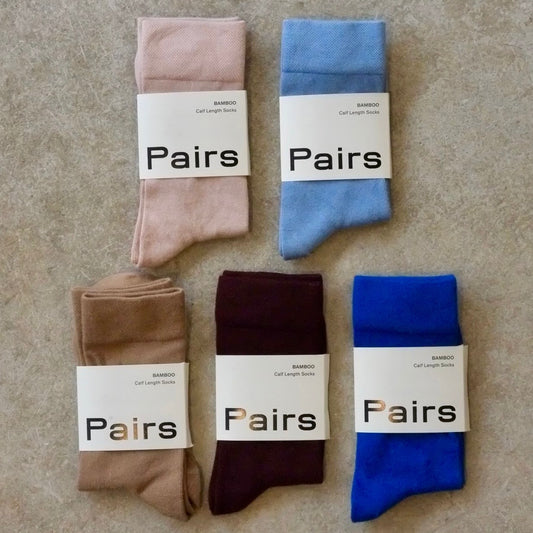 Five pairs of socks in different colors with 'Pairs' labels on a beige surface.