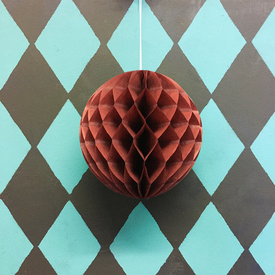 Chestnut paper honeycomb ball ornament on a diamond patterned background