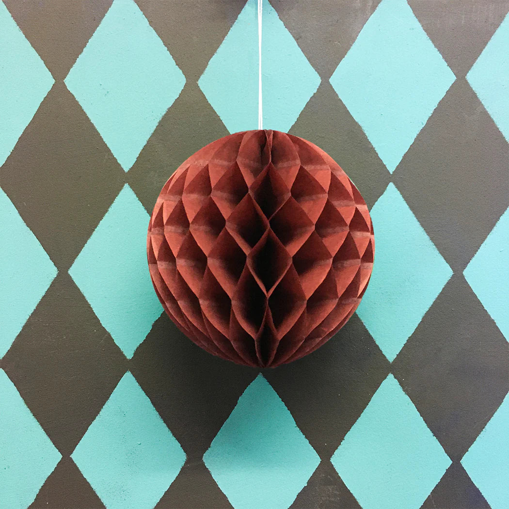 Chestnut paper honeycomb ball ornament on a diamond patterned background