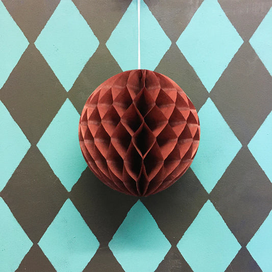 Chestnut paper honeycomb ball ornament on a diamond patterned background