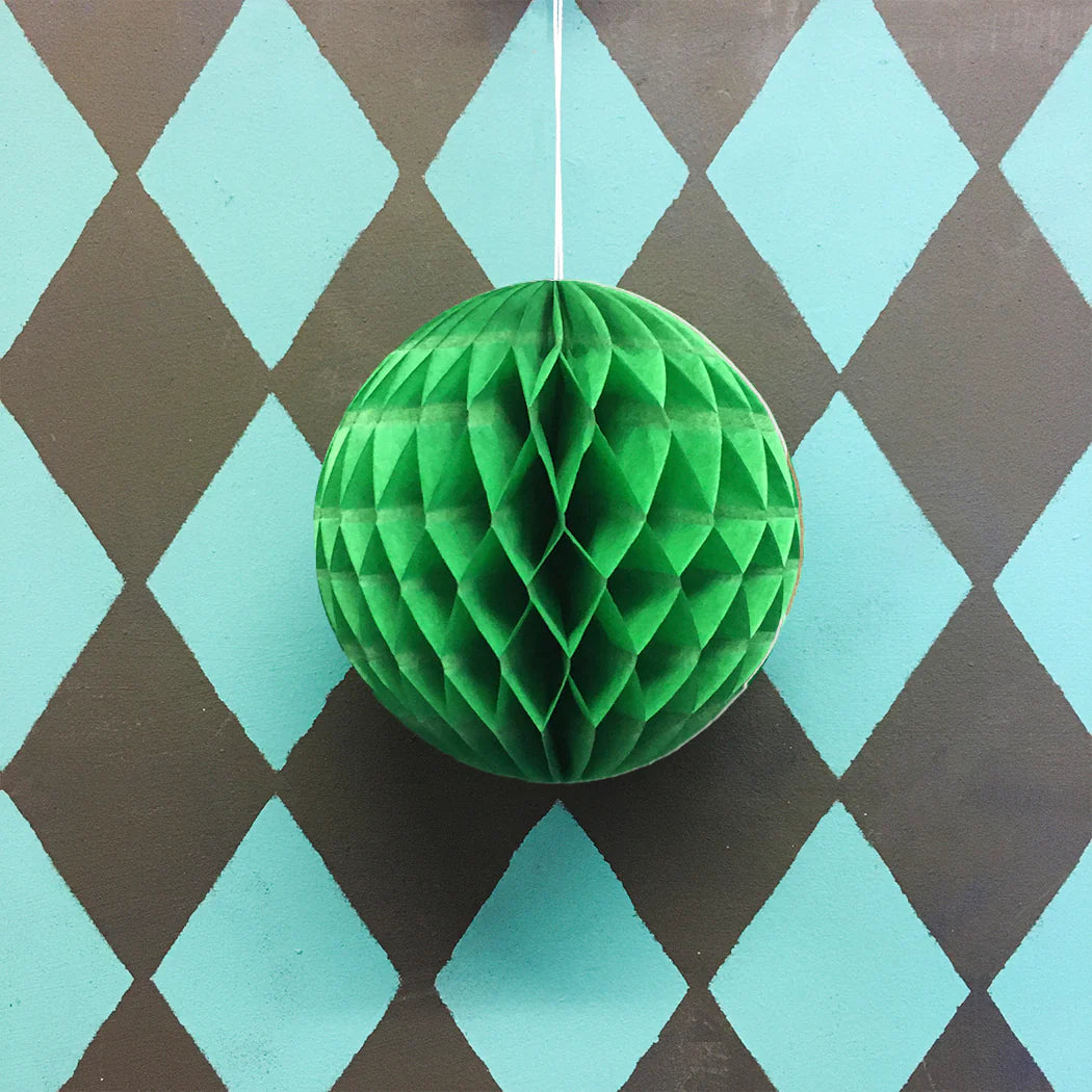 Green paper honeycomb ball hanging against a diamond-patterned background