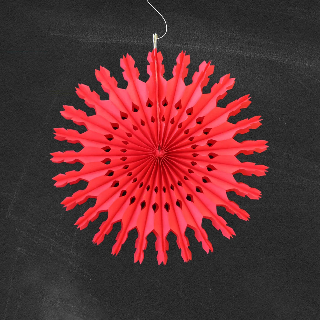 Red paper snowflake decoration hanging against a black background