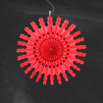 Red paper snowflake decoration hanging against a black background