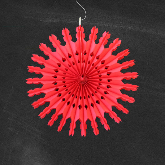 Red paper snowflake decoration hanging against a black background