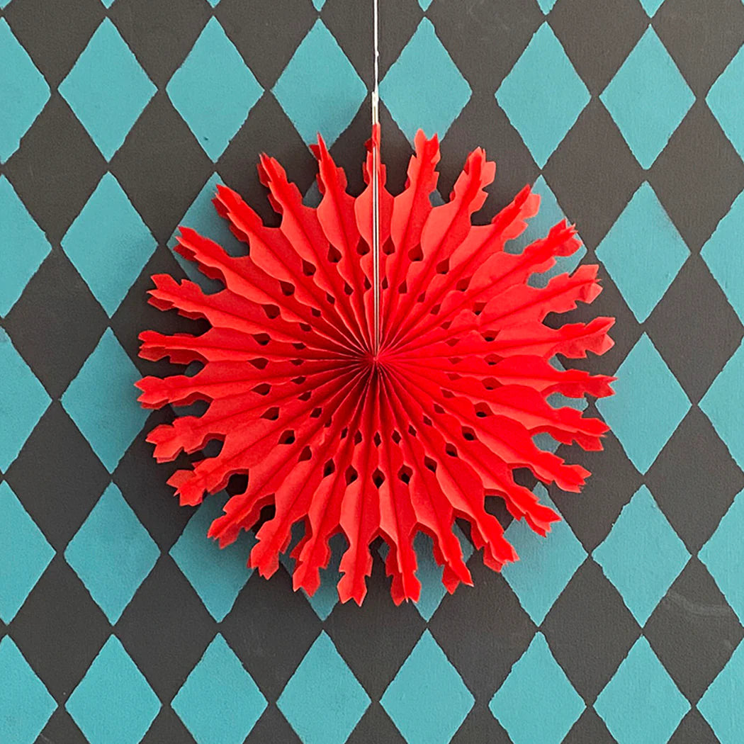 Red paper fan decoration hanging on a black and blue checkered background