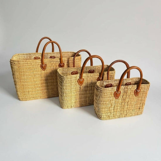 Three woven baskets with brown handles on a light gray background