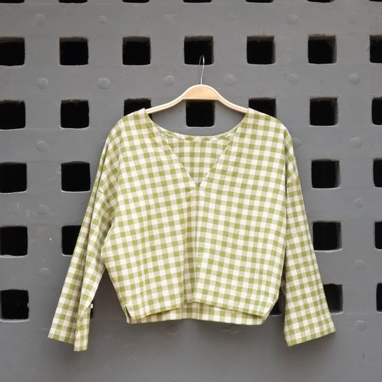 Green checkered top on a grey door background 