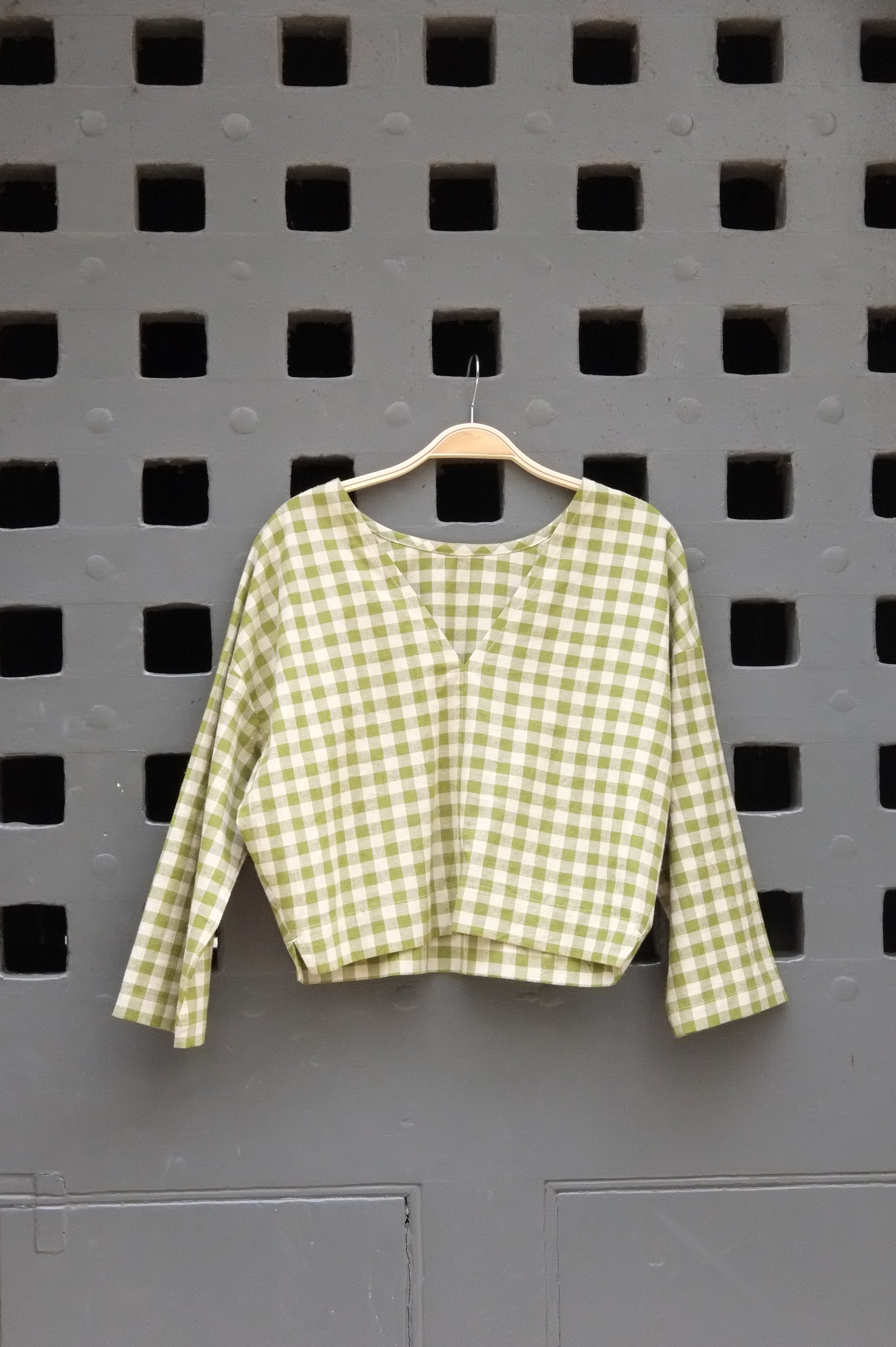 Green checkered top on a grey door background 