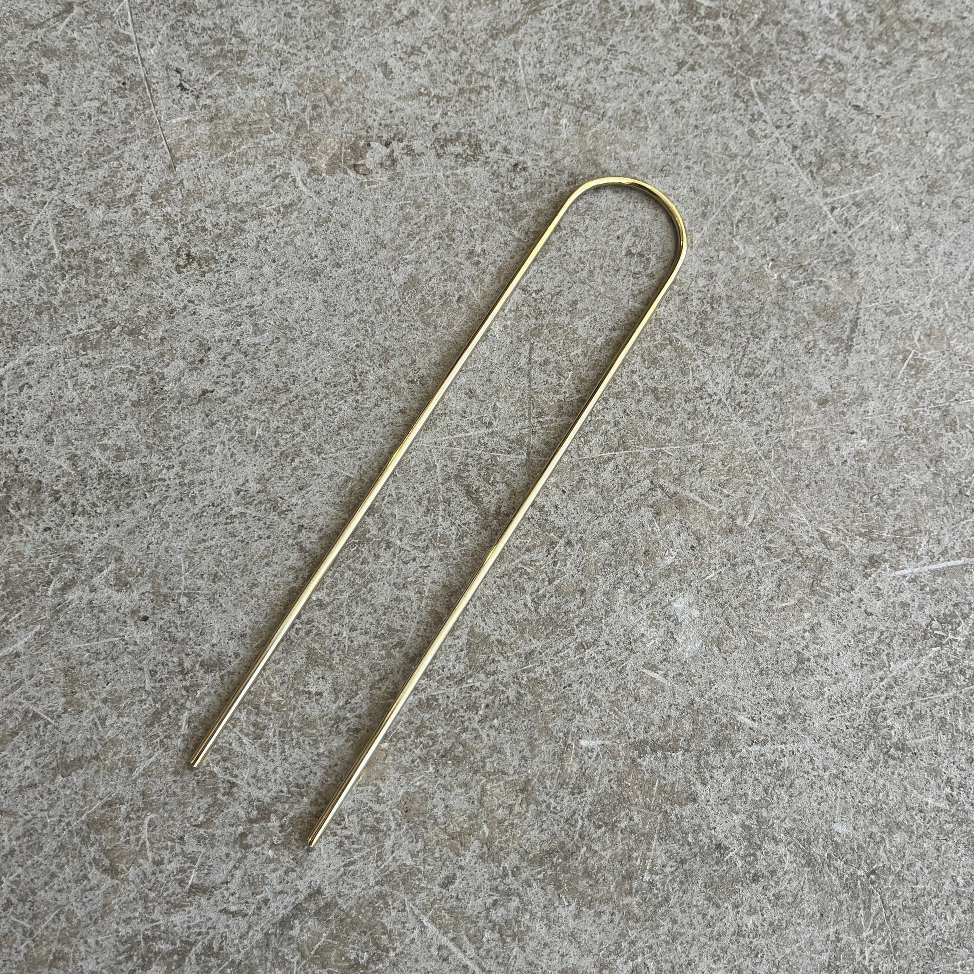 A brass hairpin on a concrete background