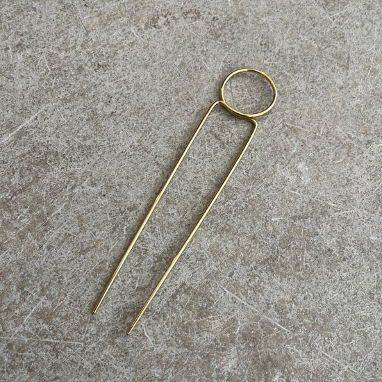 a round brass hairpin on a concrete background