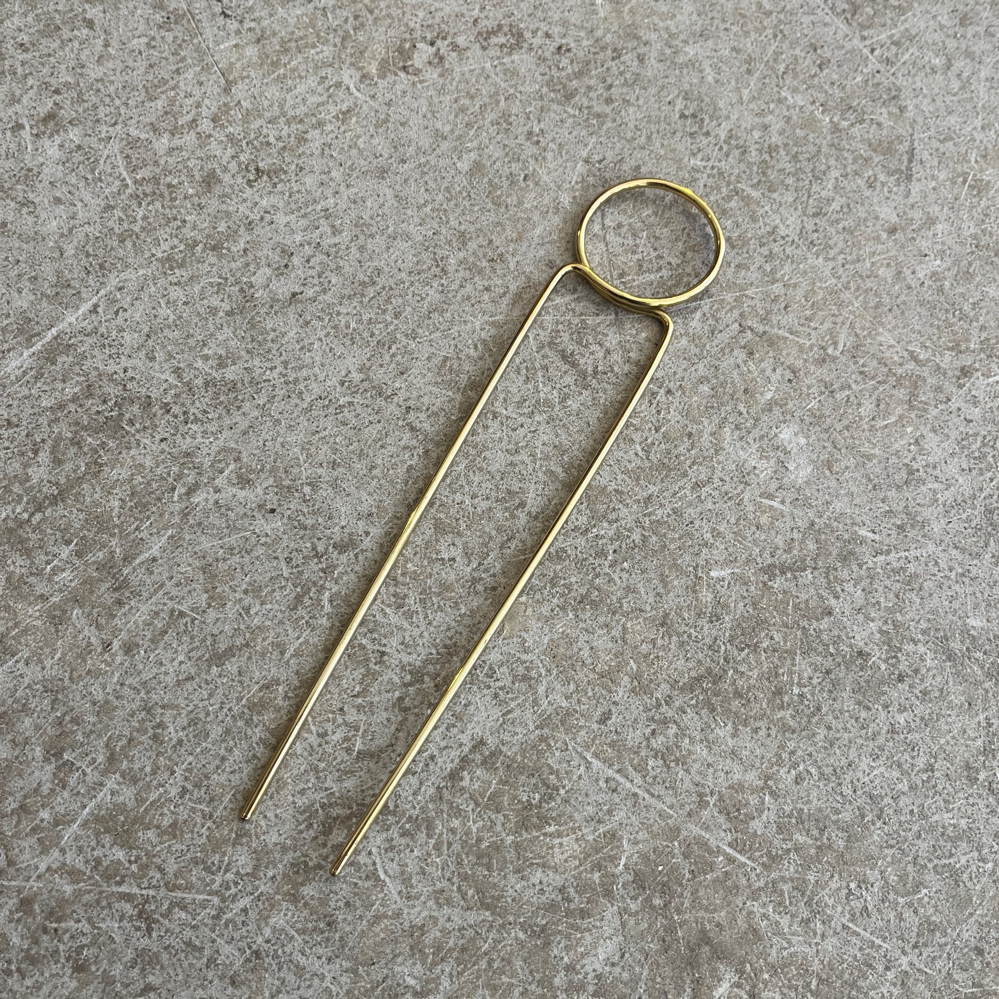 a round brass hairpin on a concrete background