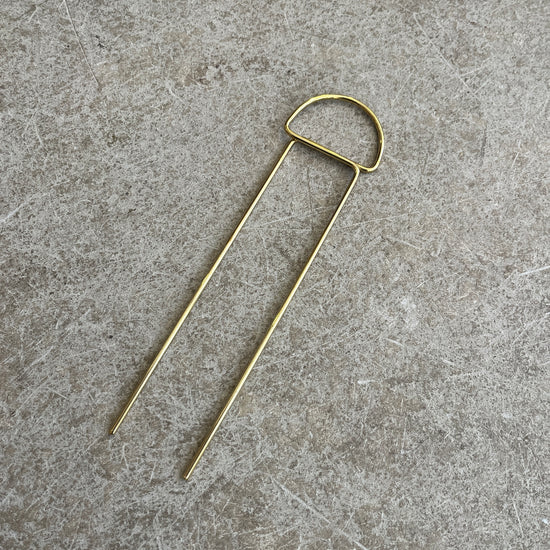 a semi circle brass hairpin on a concrete background