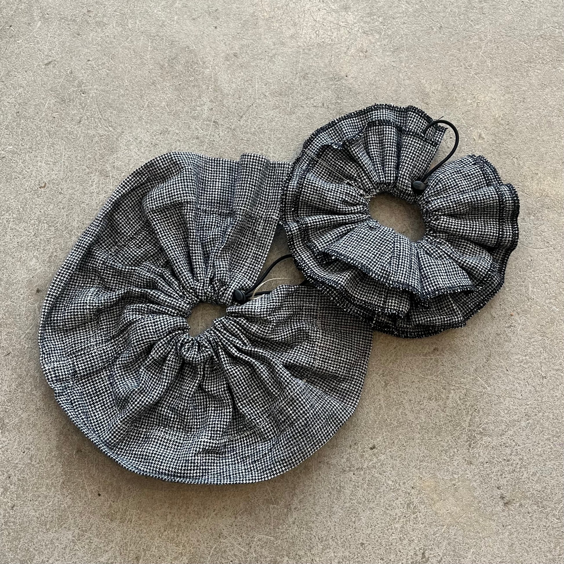 Two black and white checkered fabric drawstrings on a beige surface