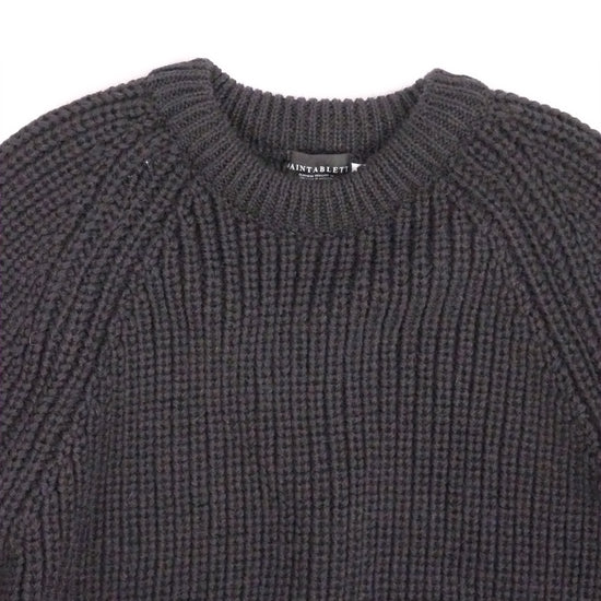Close-up of a dark gray knit sweater on a white background