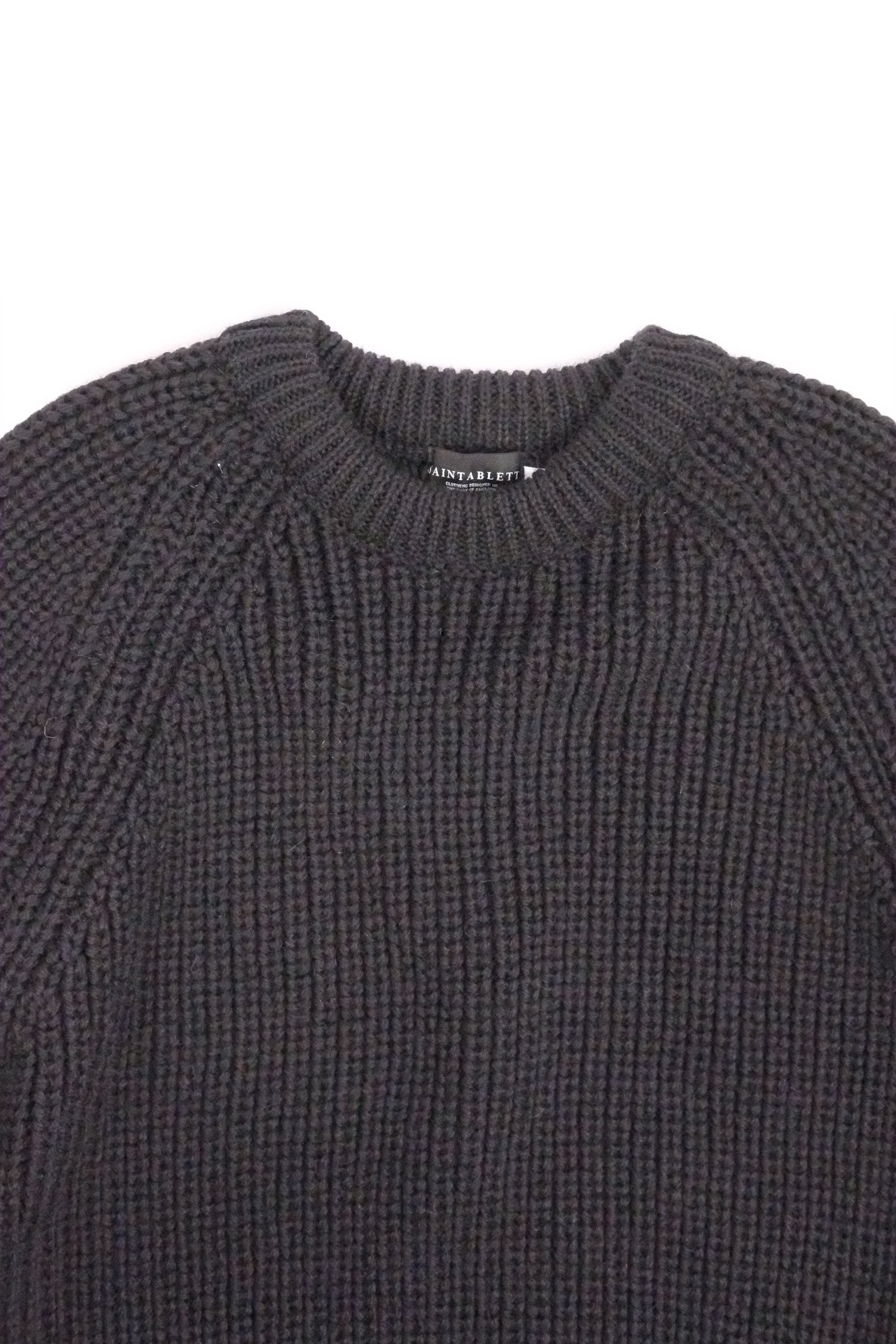 Close-up of a dark gray knit sweater on a white background