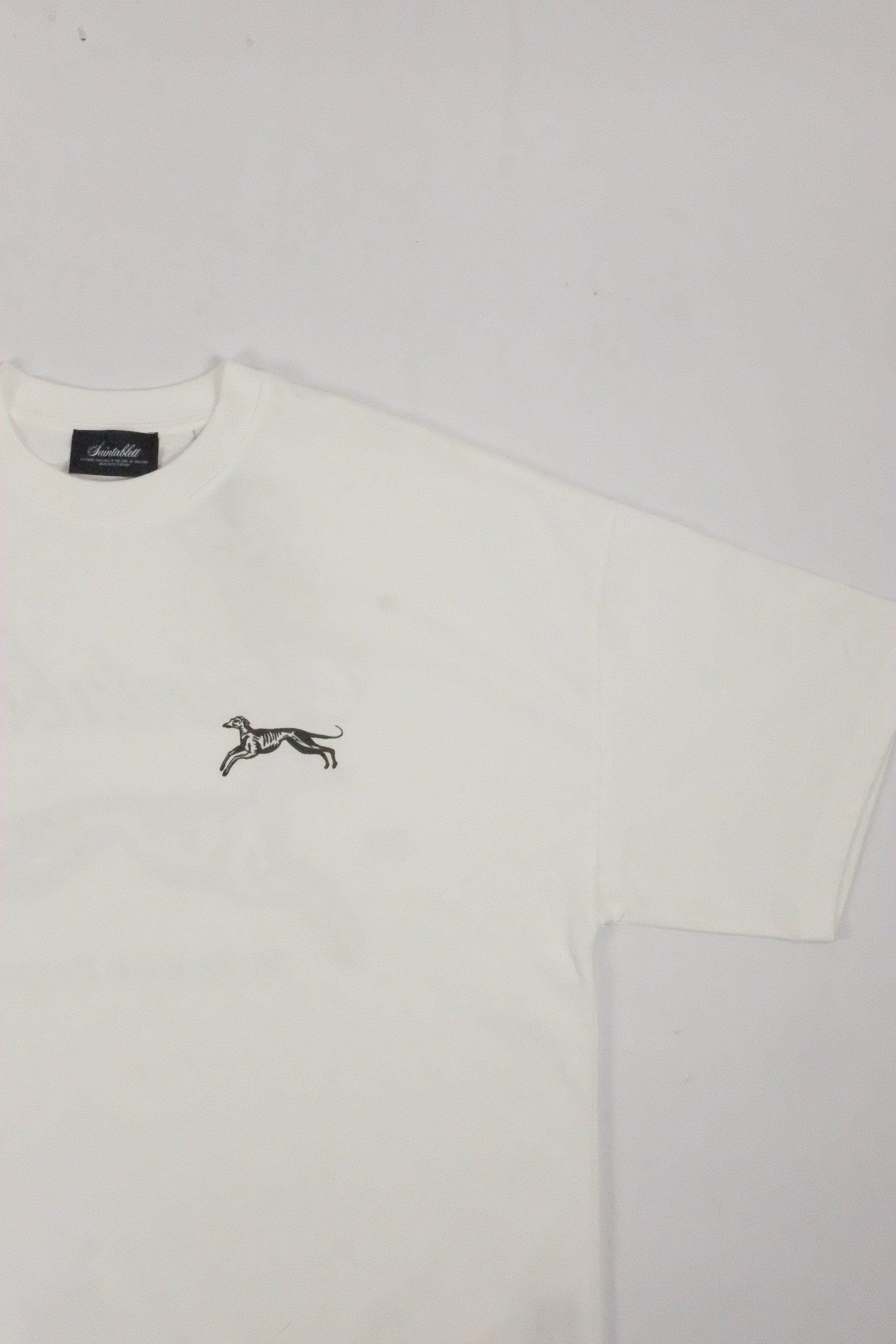 White polo shirt with a small logo on a light gray background