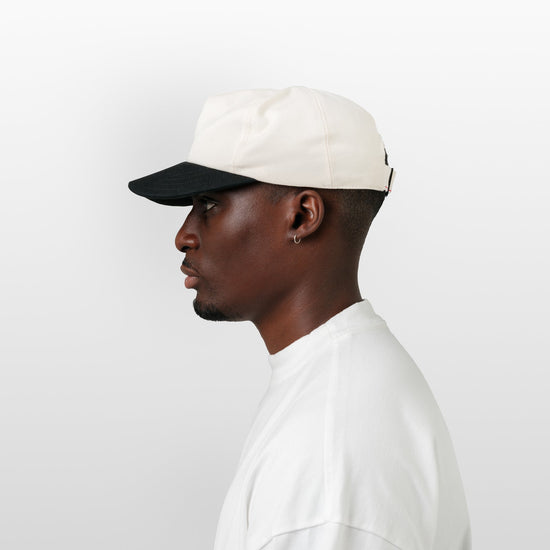 Man wearing a white cap and white shirt on a light gray background