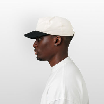 Man wearing a white cap and white shirt on a light gray background